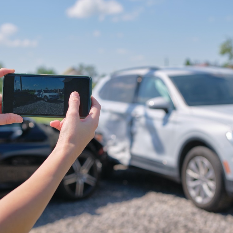 Female driver hands photographing on sellphone camera wrecked vehicles on street side for insurance