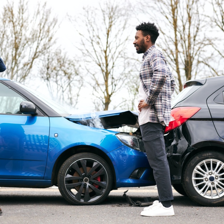 Senior Male And Younger Male Drivers Get Out Of Cars And Inspect Damage After Traffic Accident