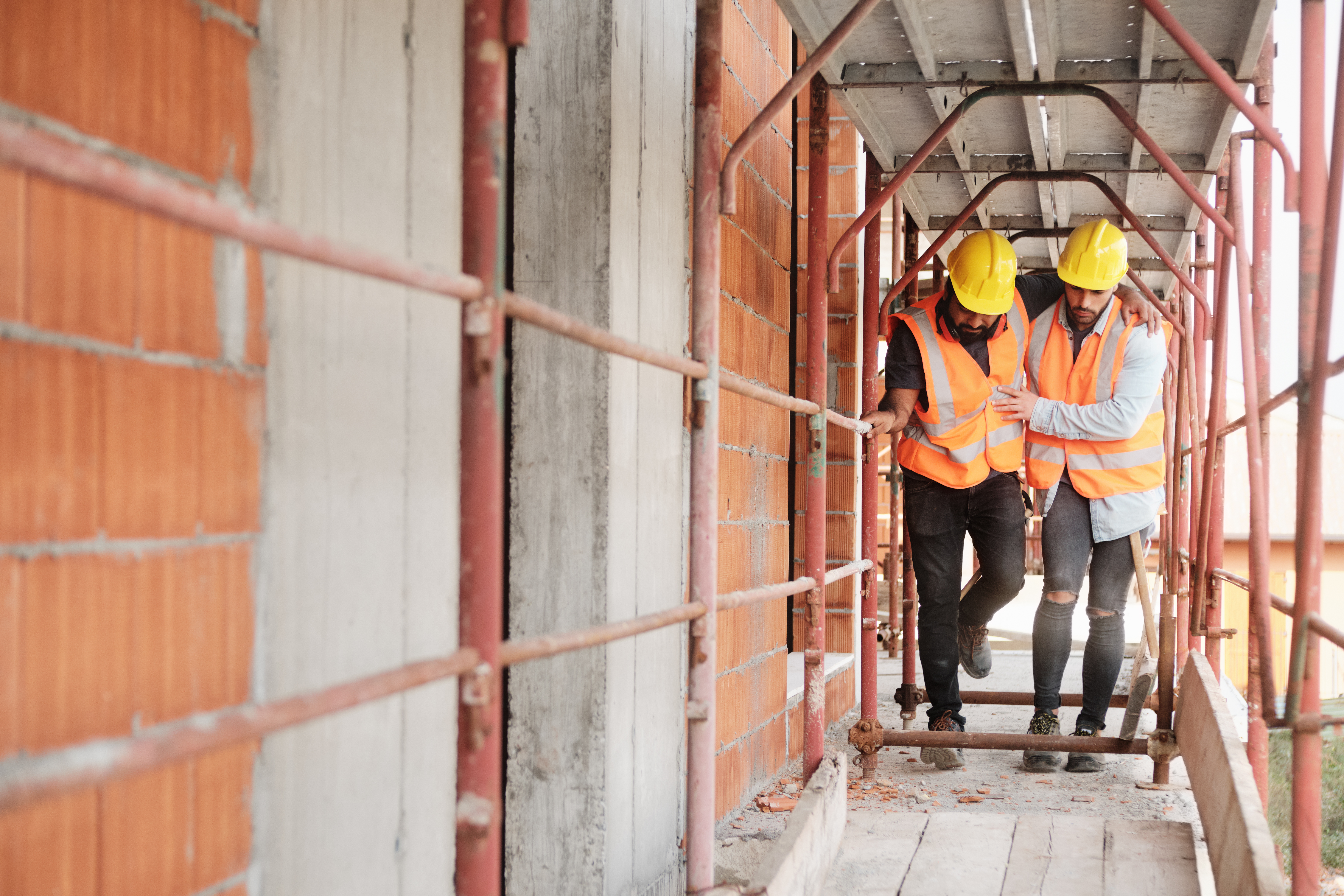 Manual Worker Helping Injured Colleague In Construction Site