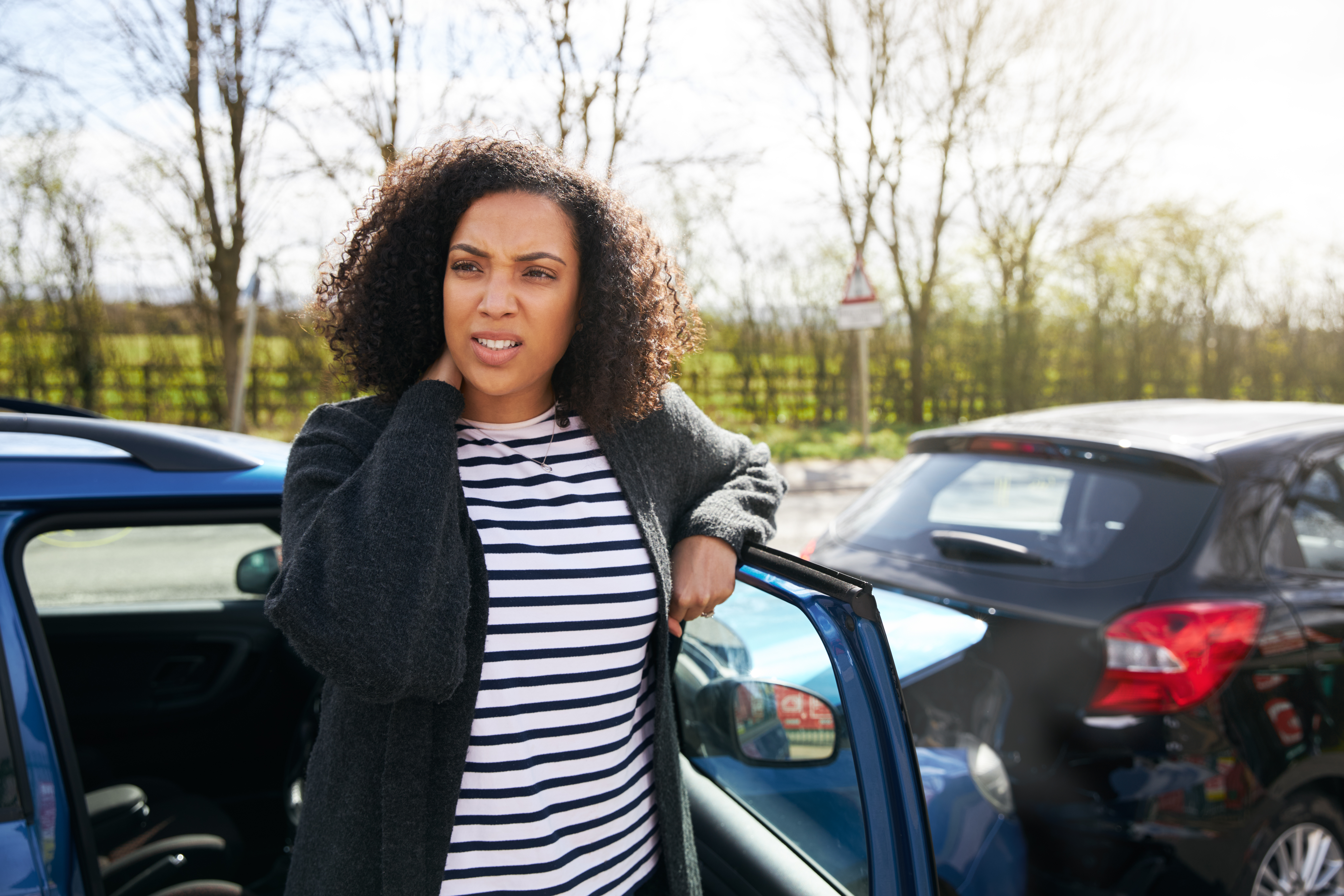 Female Driver With Whiplash Injury Standing By Damaged Car After Road Traffic Accident