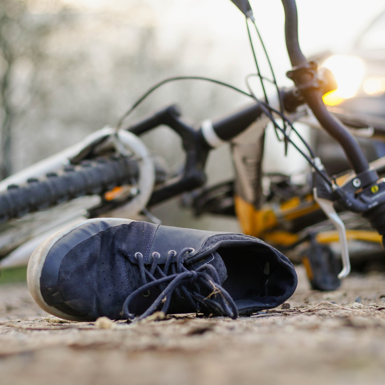 Close-up of a sneakers on the road near bicycle after car accident.