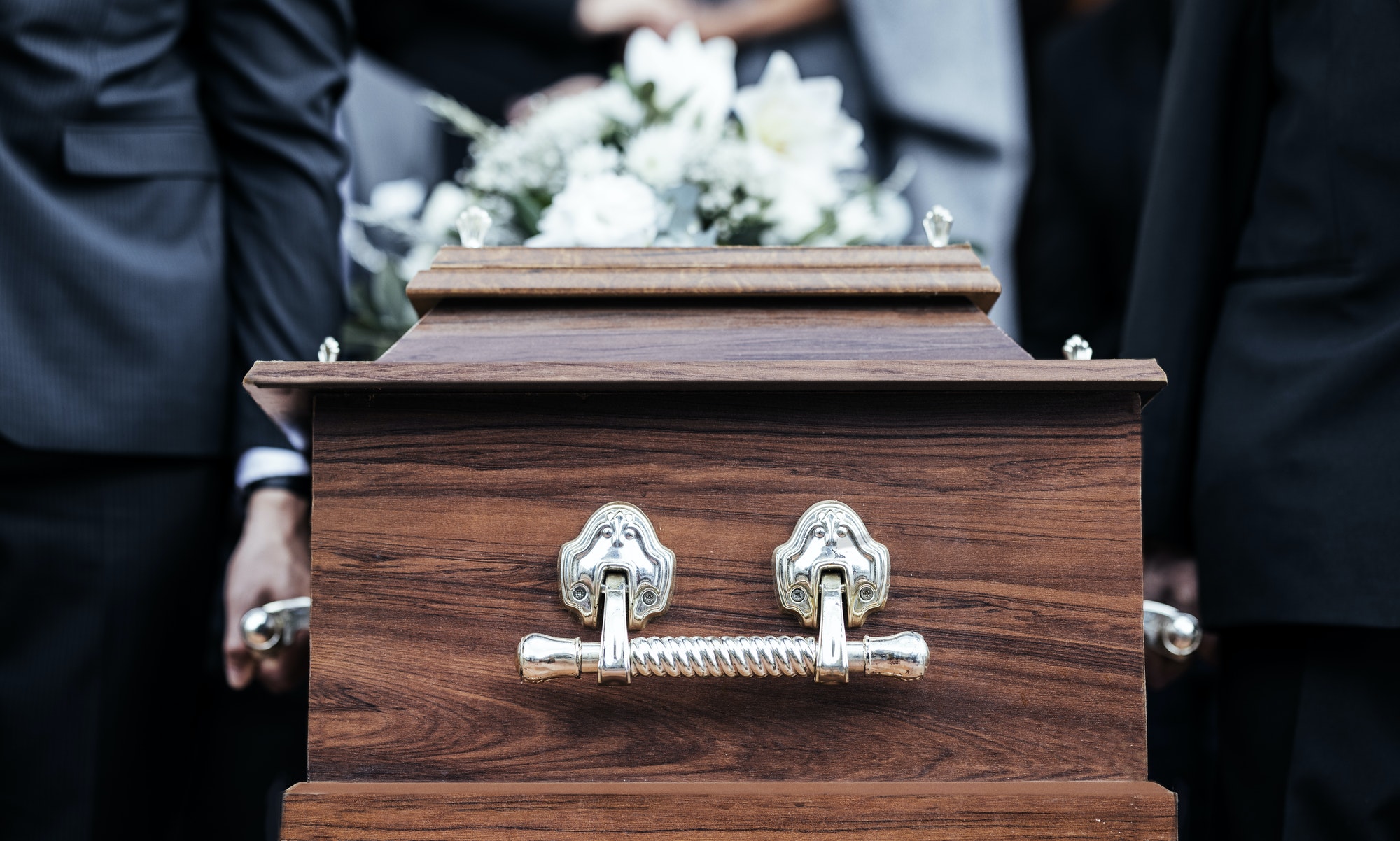 Coffin, people and funeral with death, grief and service with family carry casket to grave outdoor.