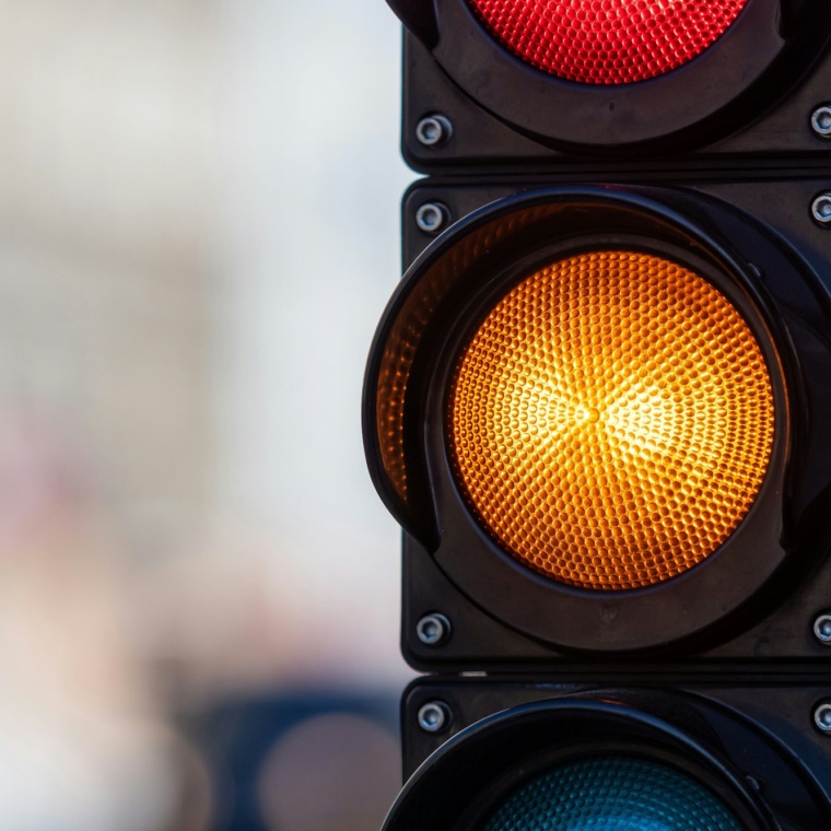 close-up of traffic semaphore with orange light on defocused city street background with copy space